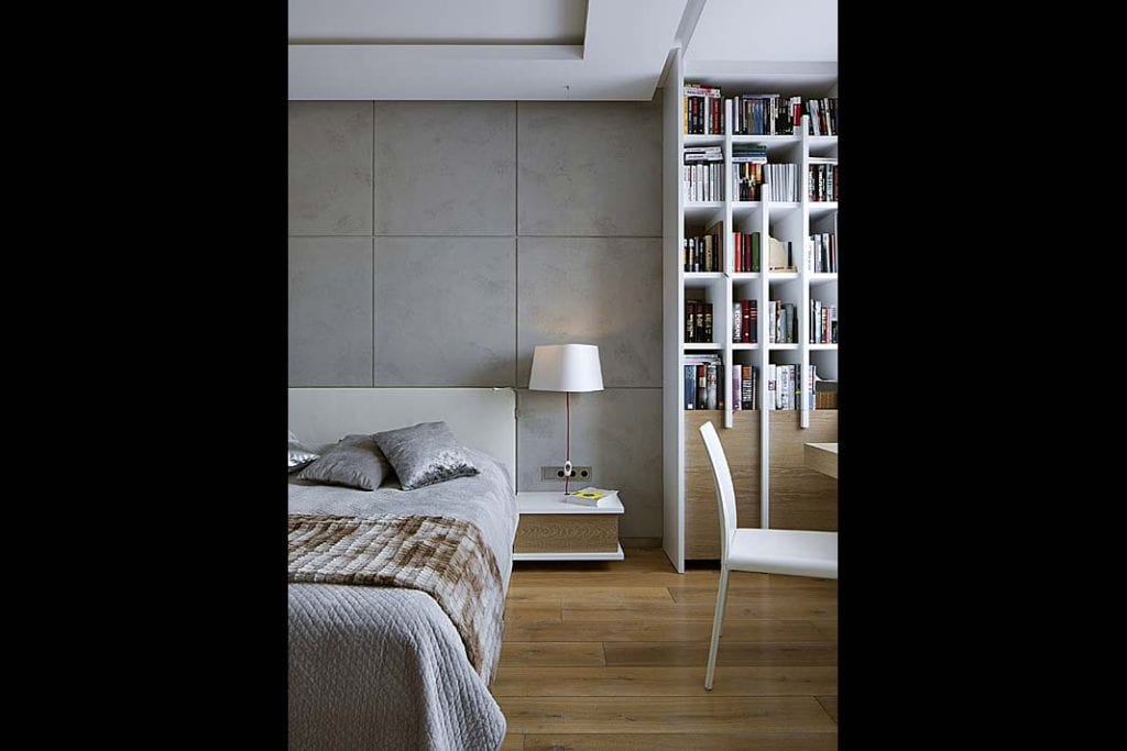 biała biblioteczka z drewnianymi wstawkami umieszczona w sypialni