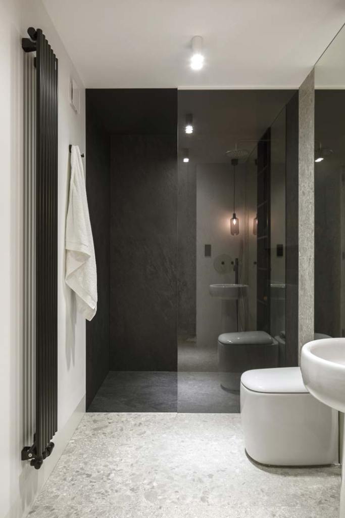 Architekci konsekwentnie wprowadzają subtelnie zaokrąglone formy do wystroju części dziennej, jak również łazienki na parterze. Wszystko po to, by nadać wnętrzom przytulny, domowy klimat. Dlatego wybrali stojącą na postumencie umywalkę SAV 40 marki Bleu Provence. Niezmiennie stosują też kolorystyczne kontrasty, zestawiając białą ceramikę z czarną baterią, grzejnikiem, akcesoriami i wbudowanym w ścianę regałem.