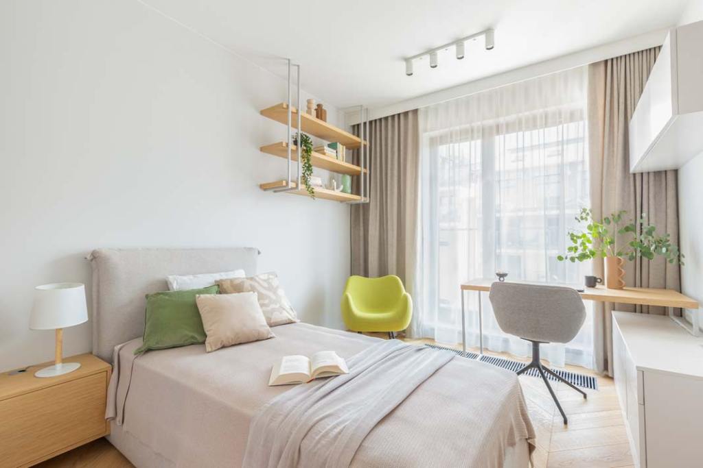 Domowe biuro w pokoju gościnnym to dość popularne rozwiązanie. Jeśli miejsca jest niewiele można zamówić blat na wymiar i zamontować go przy oknie. W tym przypadku kolor płyty meblowej, z której wykonano biurko, wiszące półki i szafkę nocną dobrano idealnie do jasnej dębowej podłogi FINISHJODŁA FRANCUSKA marki Finishparkiet. Projekt: Gama Design