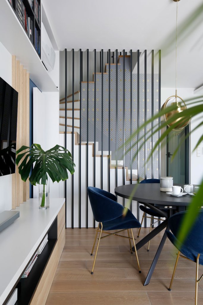 schody oddzielono od salonu za pomocą dekoracyjnych listew. Ażurowa przegroda nie ogranicza przepływu naturalnego światła_MIKOŁAJSKAstudio